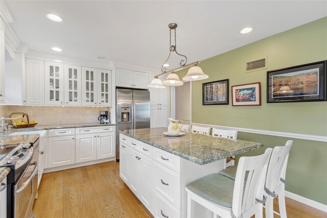 kitchen with visible vents, light wood finished floors, a breakfast bar, a sink, and stainless steel appliances