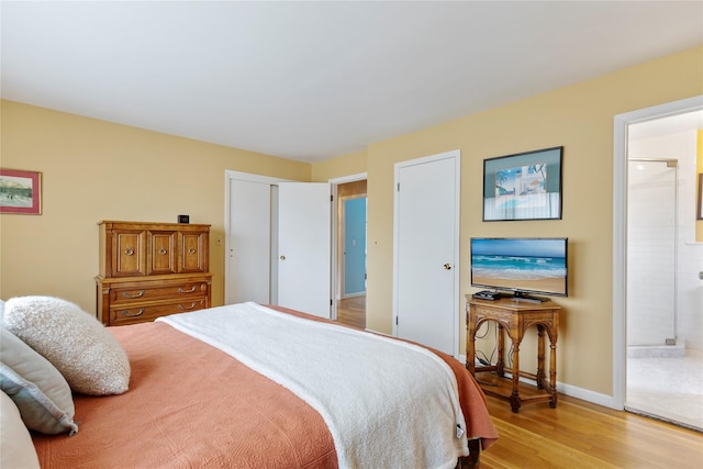 bedroom featuring light wood-style floors, baseboards, a closet, and connected bathroom