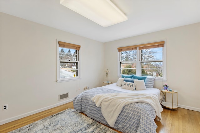 bedroom featuring visible vents, baseboards, and wood finished floors