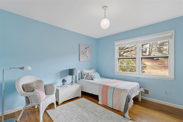 bedroom with visible vents, baseboards, and wood finished floors