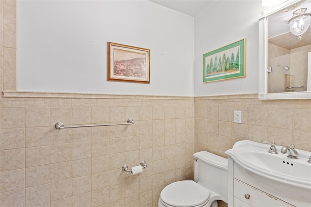 bathroom with a wainscoted wall, toilet, tile walls, and vanity