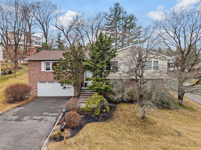 view of front of property with brick siding, driveway, stairs, and a garage