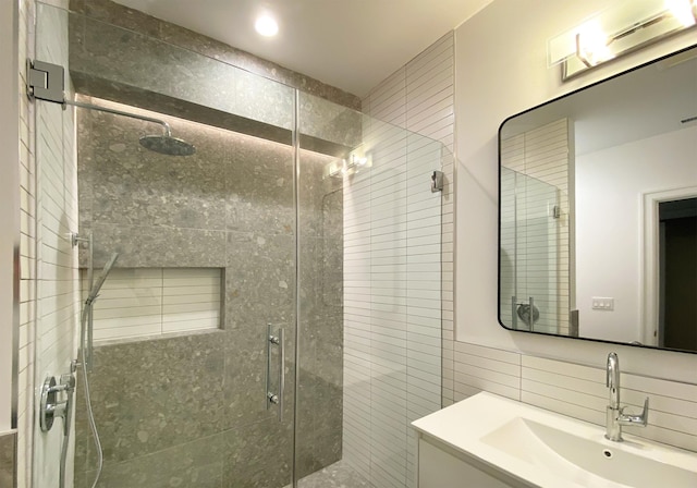 bathroom featuring vanity, tasteful backsplash, tile walls, and walk in shower