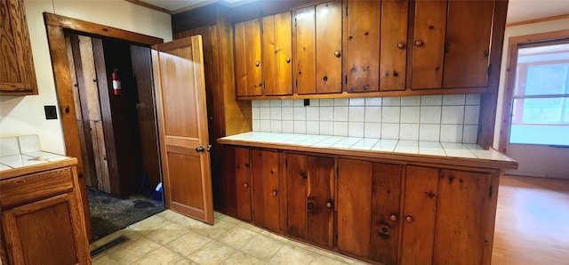 kitchen featuring tile countertops, decorative backsplash, and ornamental molding