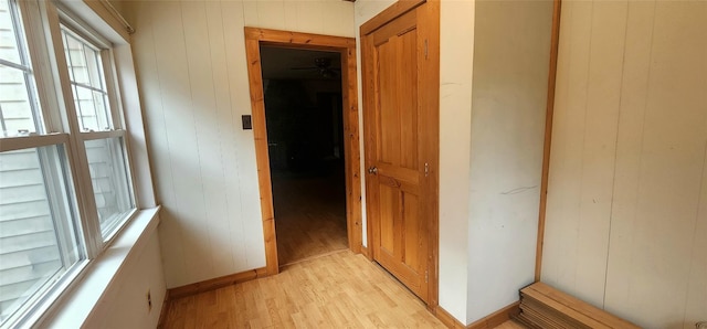 hall featuring light hardwood / wood-style floors and wooden walls