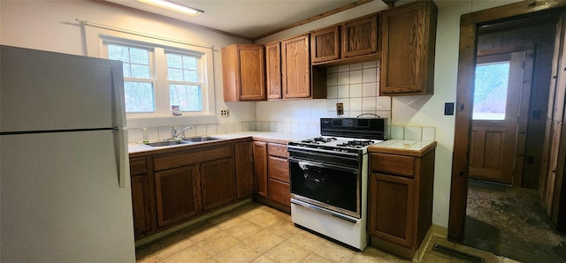 71 Peekamoose Rd, Sundown, NY 12740 - kitchen with freestanding refrigerator, range with gas cooktop, tile countertops, a sink, and brown cabinetry