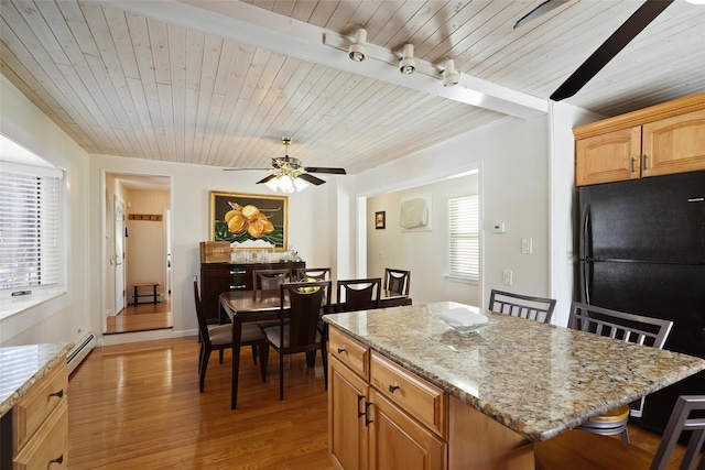 kitchen featuring a breakfast bar, a baseboard radiator, a center island, light hardwood / wood-style floors, and black fridge