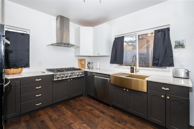 kitchen featuring dark wood-type flooring, sink, wall chimney exhaust hood, appliances with stainless steel finishes, and light stone counters