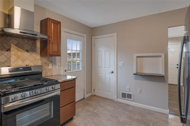 kitchen featuring tasteful backsplash, visible vents, brown cabinetry, stainless steel gas range, and wall chimney exhaust hood