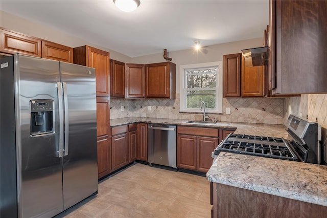 kitchen featuring stainless steel appliances, tasteful backsplash, a sink, and light stone countertops