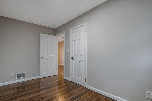 unfurnished bedroom with dark wood-type flooring, visible vents, and baseboards