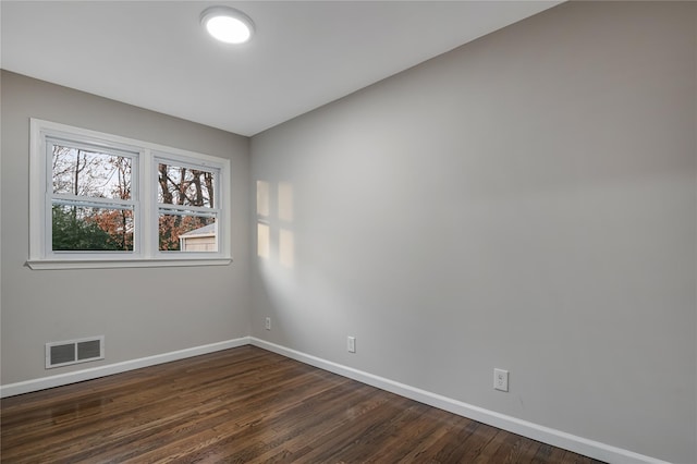 unfurnished room featuring dark wood-style floors, baseboards, and visible vents