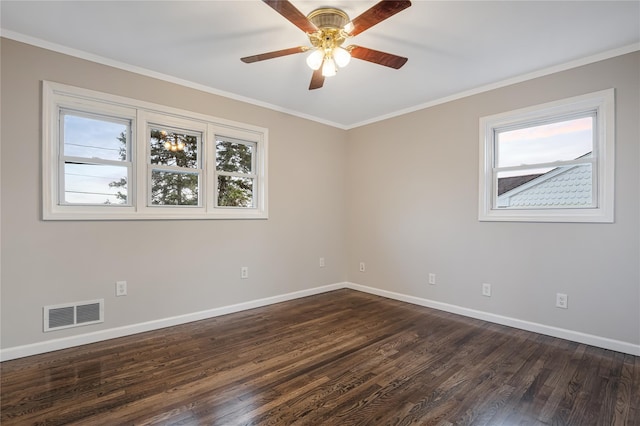 empty room with crown molding, visible vents, dark wood-type flooring, and a wealth of natural light