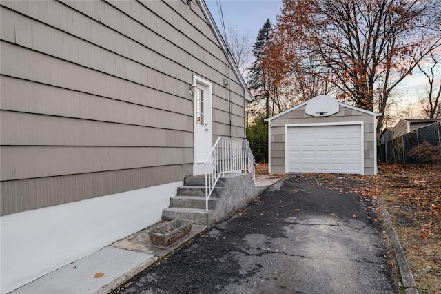 exterior space with a detached garage, aphalt driveway, and an outbuilding