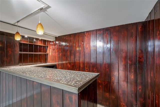 kitchen with decorative light fixtures, wooden walls, dark brown cabinets, and open shelves