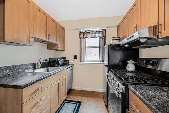 kitchen featuring dark stone counters, sink, stainless steel appliances, and range hood