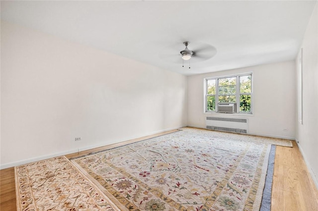 empty room with wood-type flooring, radiator, and ceiling fan