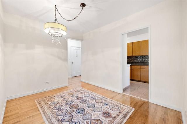 empty room with light hardwood / wood-style flooring and a chandelier