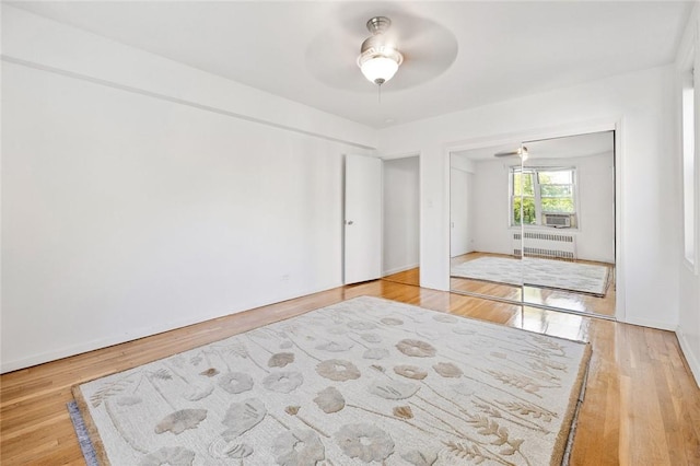 bedroom featuring radiator, hardwood / wood-style flooring, a closet, and ceiling fan