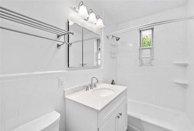 full bathroom with vanity, tiled shower / bath combo, tile walls, and toilet