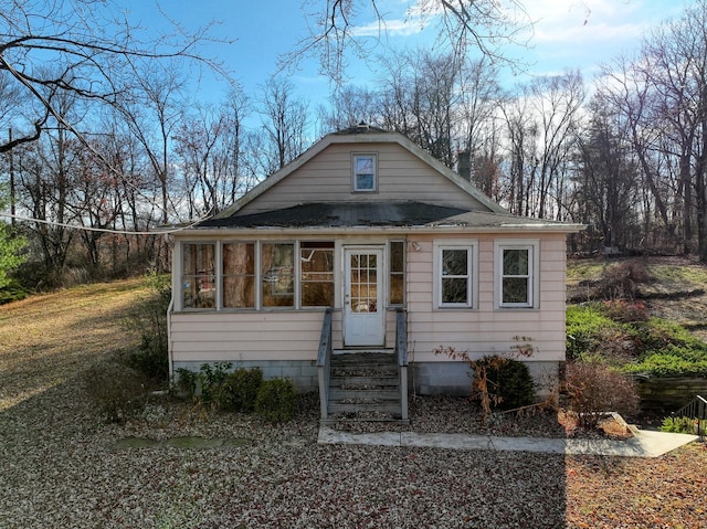 bungalow-style home featuring a sunroom and a front yard