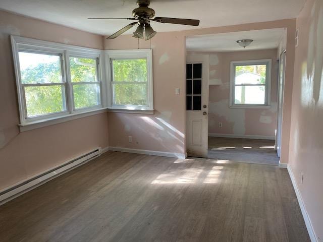 unfurnished room featuring dark hardwood / wood-style floors, ceiling fan, and a baseboard heating unit