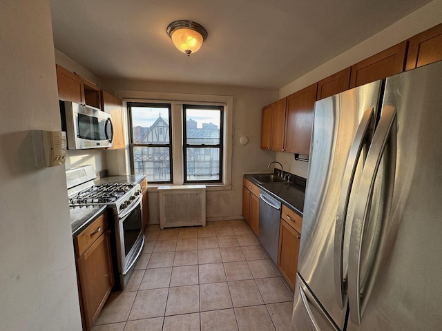 kitchen with sink, light tile patterned flooring, stainless steel appliances, and radiator heating unit