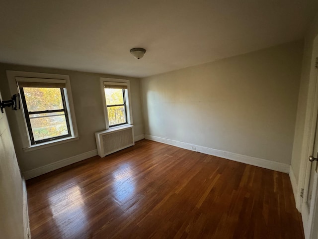 spare room with dark hardwood / wood-style flooring and radiator