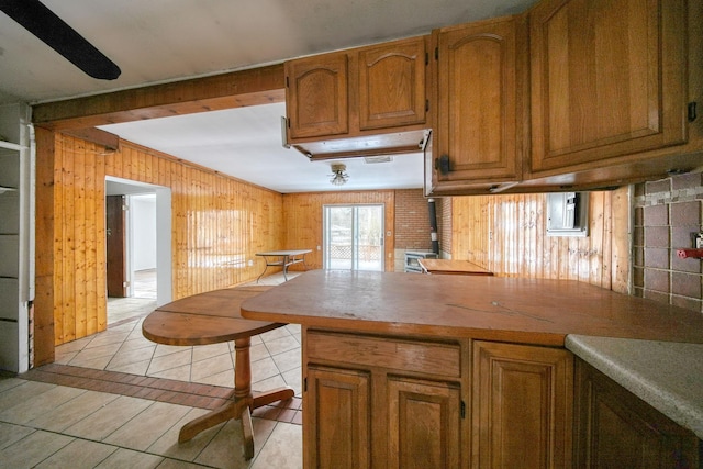 kitchen with kitchen peninsula, wooden walls, and light tile patterned flooring