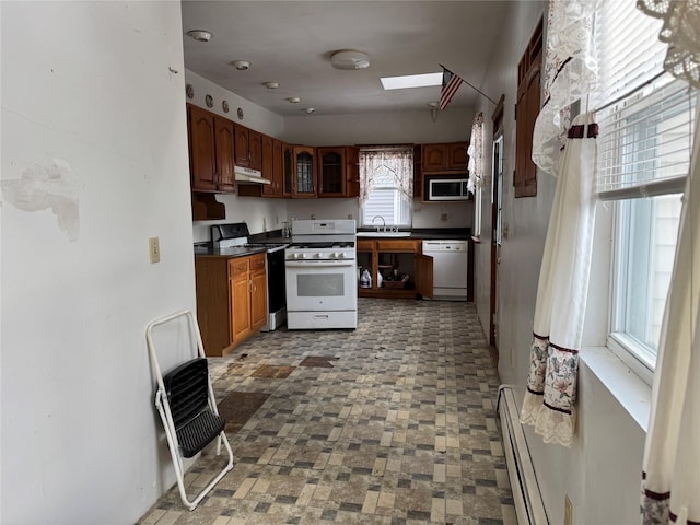 kitchen featuring white appliances, a baseboard radiator, a skylight, and sink