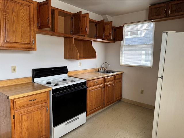 kitchen featuring electric stove, sink, and white fridge