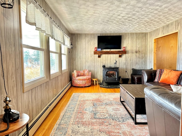 living room featuring a baseboard heating unit, light hardwood / wood-style flooring, a textured ceiling, and wooden walls