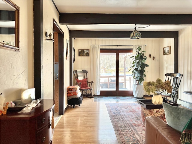 doorway to outside featuring light wood-type flooring, beamed ceiling, and wooden walls