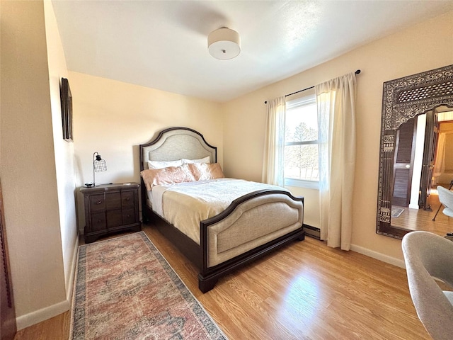 bedroom with a baseboard heating unit and wood-type flooring