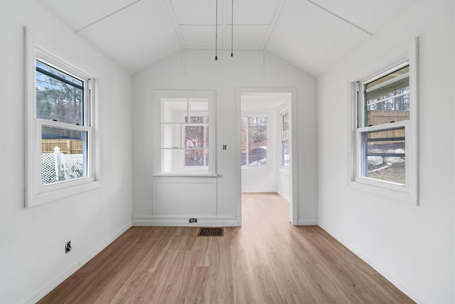 empty room with light hardwood / wood-style flooring, a wealth of natural light, and lofted ceiling