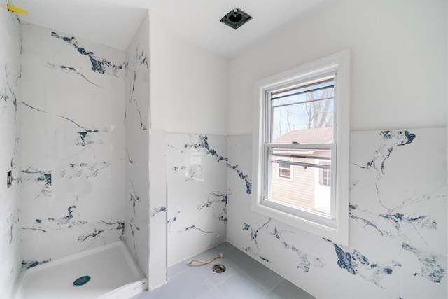 bathroom with tiled shower and tile patterned floors