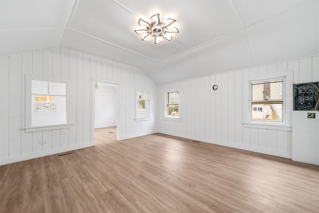 unfurnished living room featuring wooden walls, lofted ceiling, and light wood-type flooring