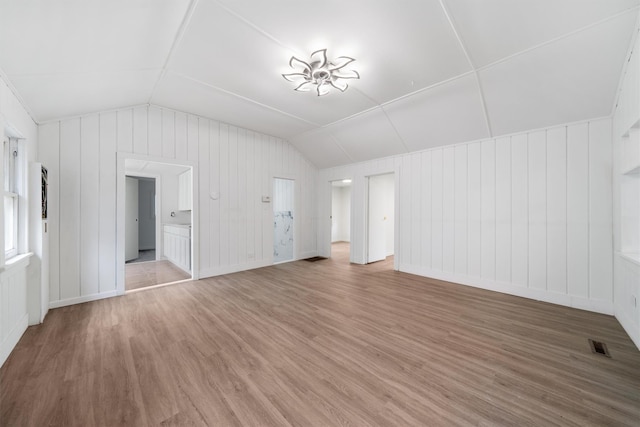 unfurnished living room with wood walls, lofted ceiling, and hardwood / wood-style flooring