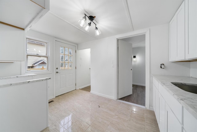 kitchen featuring light hardwood / wood-style floors, light stone counters, white cabinetry, and sink