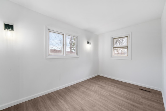 spare room featuring light hardwood / wood-style floors and a healthy amount of sunlight