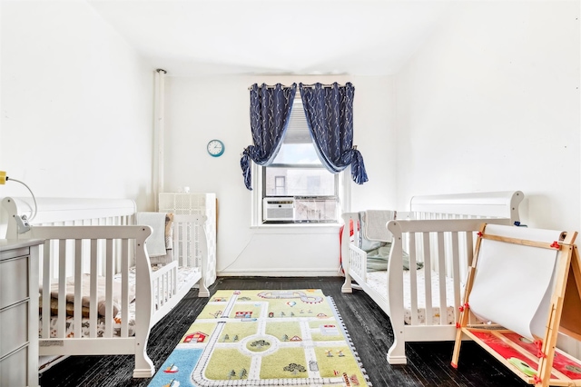 bedroom featuring dark hardwood / wood-style flooring and a nursery area