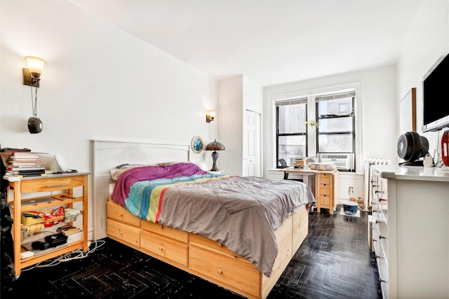 bedroom featuring dark parquet floors, a closet, radiator, and cooling unit