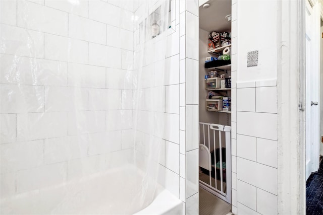 bathroom with tiled shower / bath and tile walls