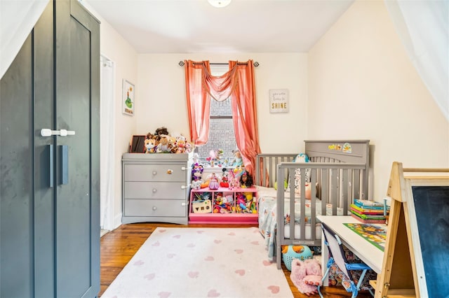 bedroom featuring dark hardwood / wood-style flooring and a nursery area