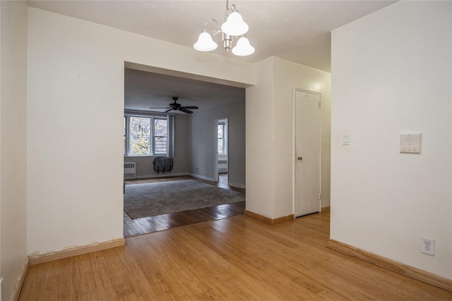 interior space featuring hardwood / wood-style floors, ceiling fan with notable chandelier, and radiator