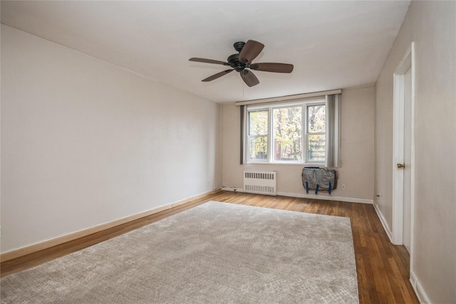 spare room with ceiling fan, wood-type flooring, and radiator