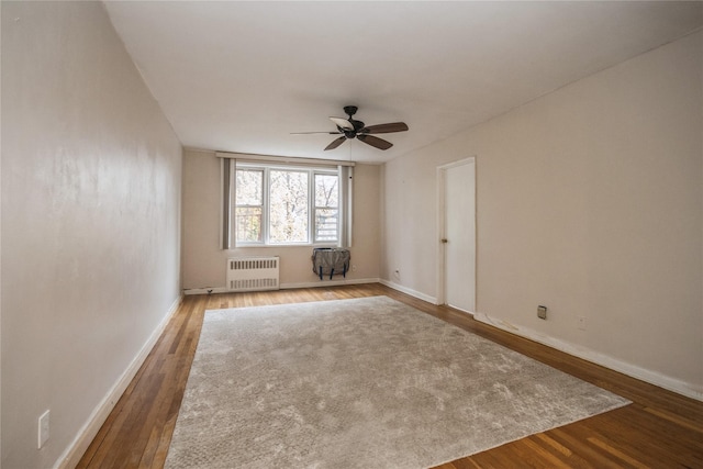 spare room featuring radiator, ceiling fan, and wood-type flooring