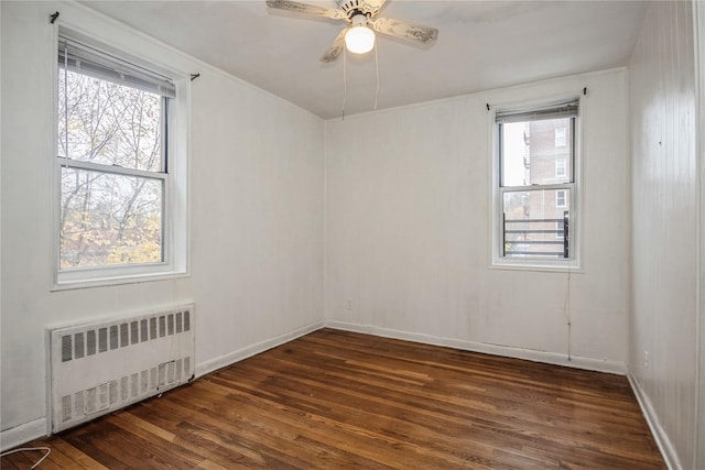 empty room featuring radiator heating unit, dark hardwood / wood-style floors, ceiling fan, and a healthy amount of sunlight