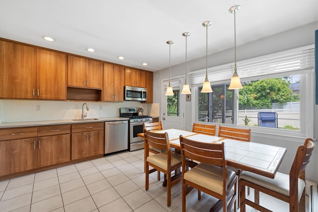 27 Stubbe Dr, Stony Point, NY 10980 - kitchen featuring appliances with stainless steel finishes, brown cabinetry, decorative backsplash, decorative light fixtures, and light tile patterned floors