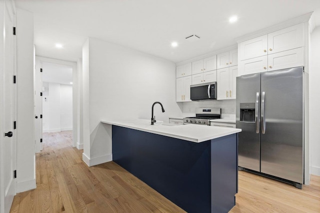 kitchen featuring sink, stainless steel appliances, light hardwood / wood-style floors, a kitchen bar, and white cabinets